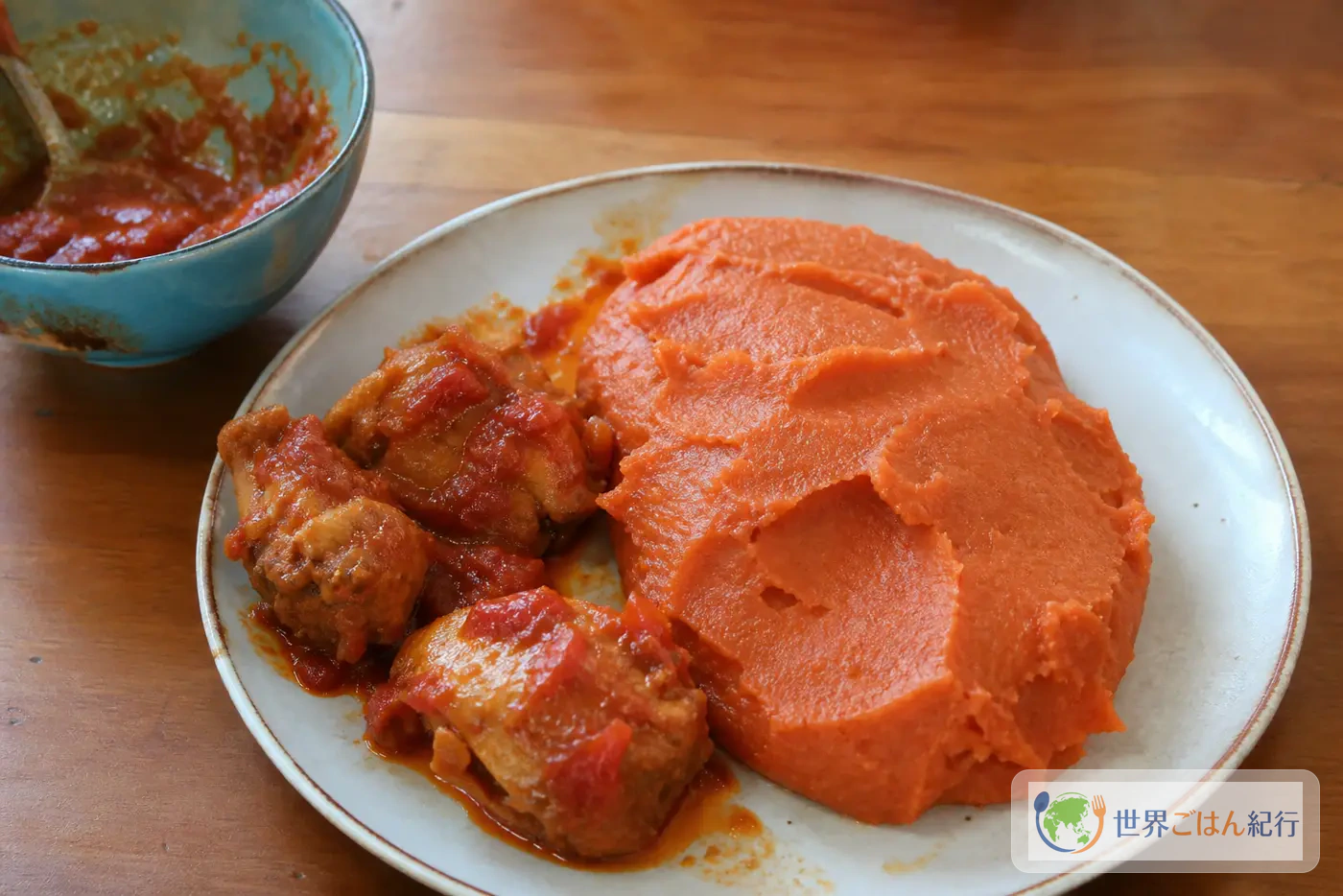 ベナンのアミウォを赤いとうもろこし粉のドームにし、鶏のトマトソースを添えた皿