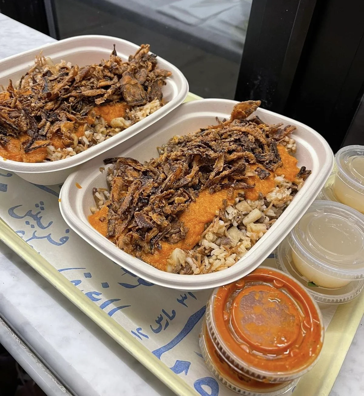 カイロの屋台で提供されるテイクアウトのコシャリ。大きなアルミ容器にフライドオニオンがたっぷり載っている