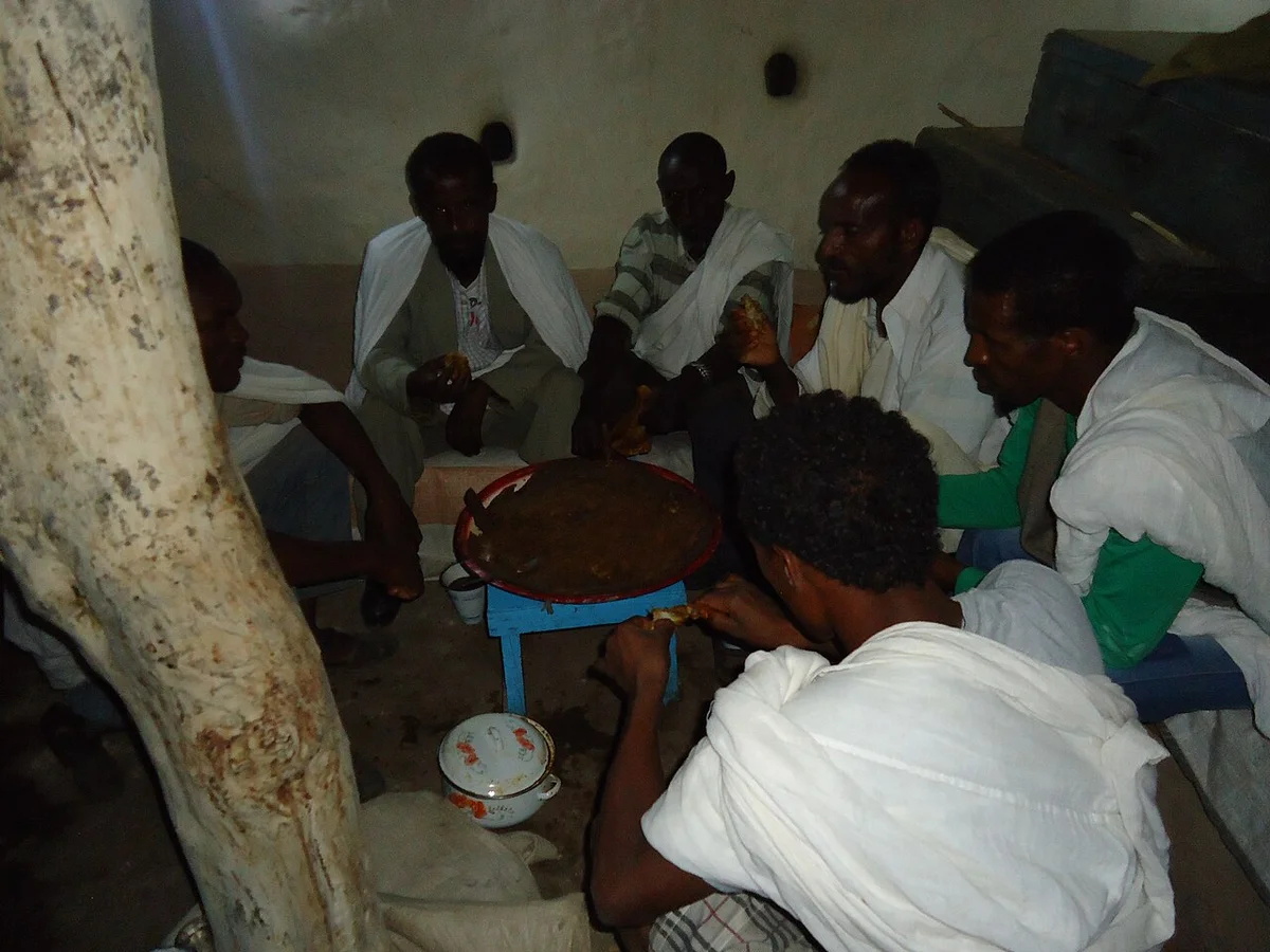 エリトリアの伝統的な食事風景。人々がインジェラを囲んで手で食べている