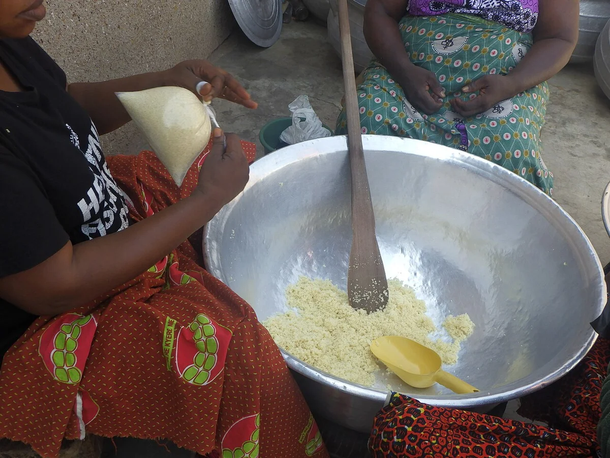 西アフリカの女性たちがアチェケを大きな鍋で調理している様子。木べらで混ぜている