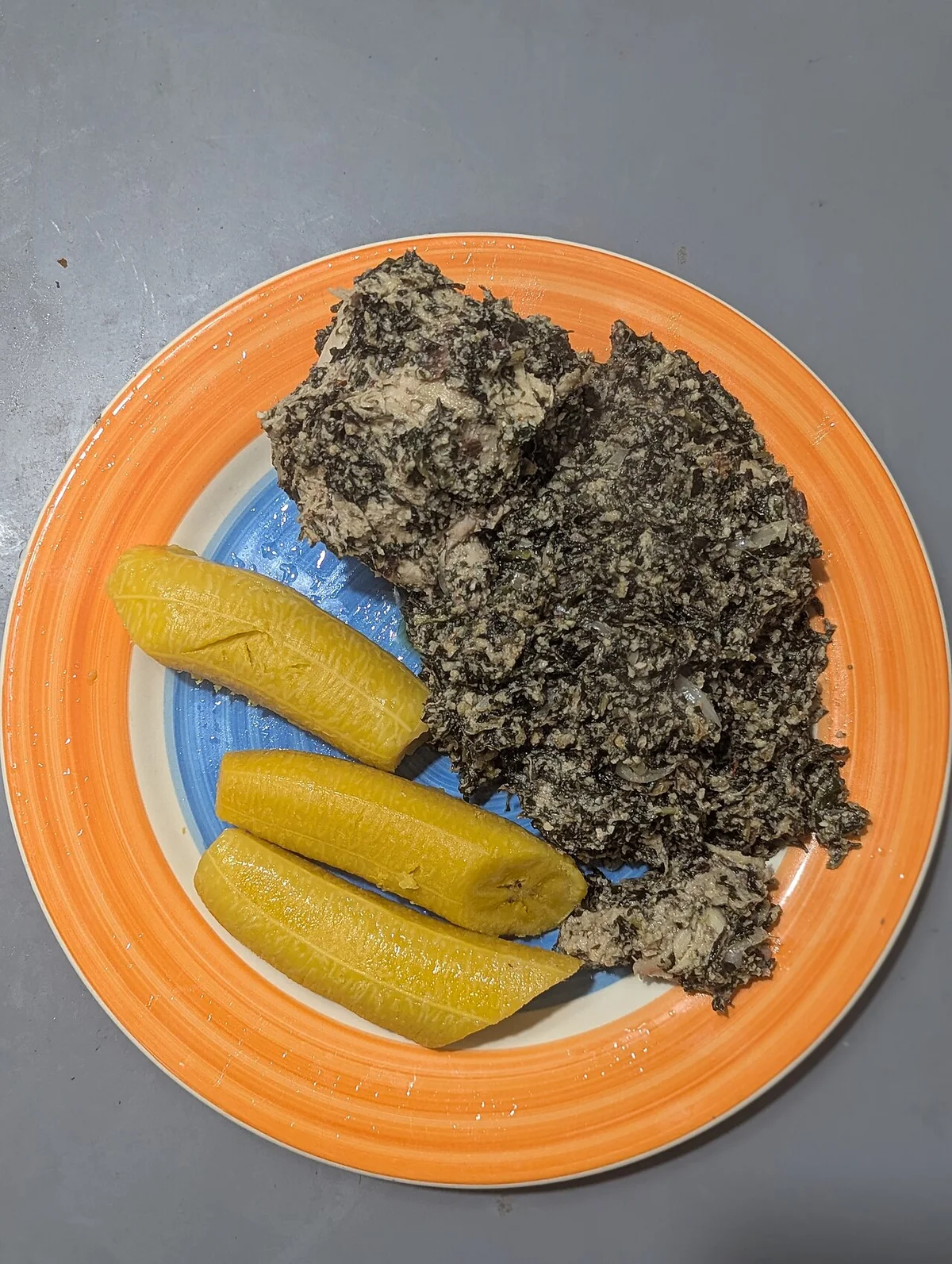 カメルーンの国民食ンドレ。ビターリーフとピーナッツの濃厚な煮込みに揚げプランテンを添えた一皿