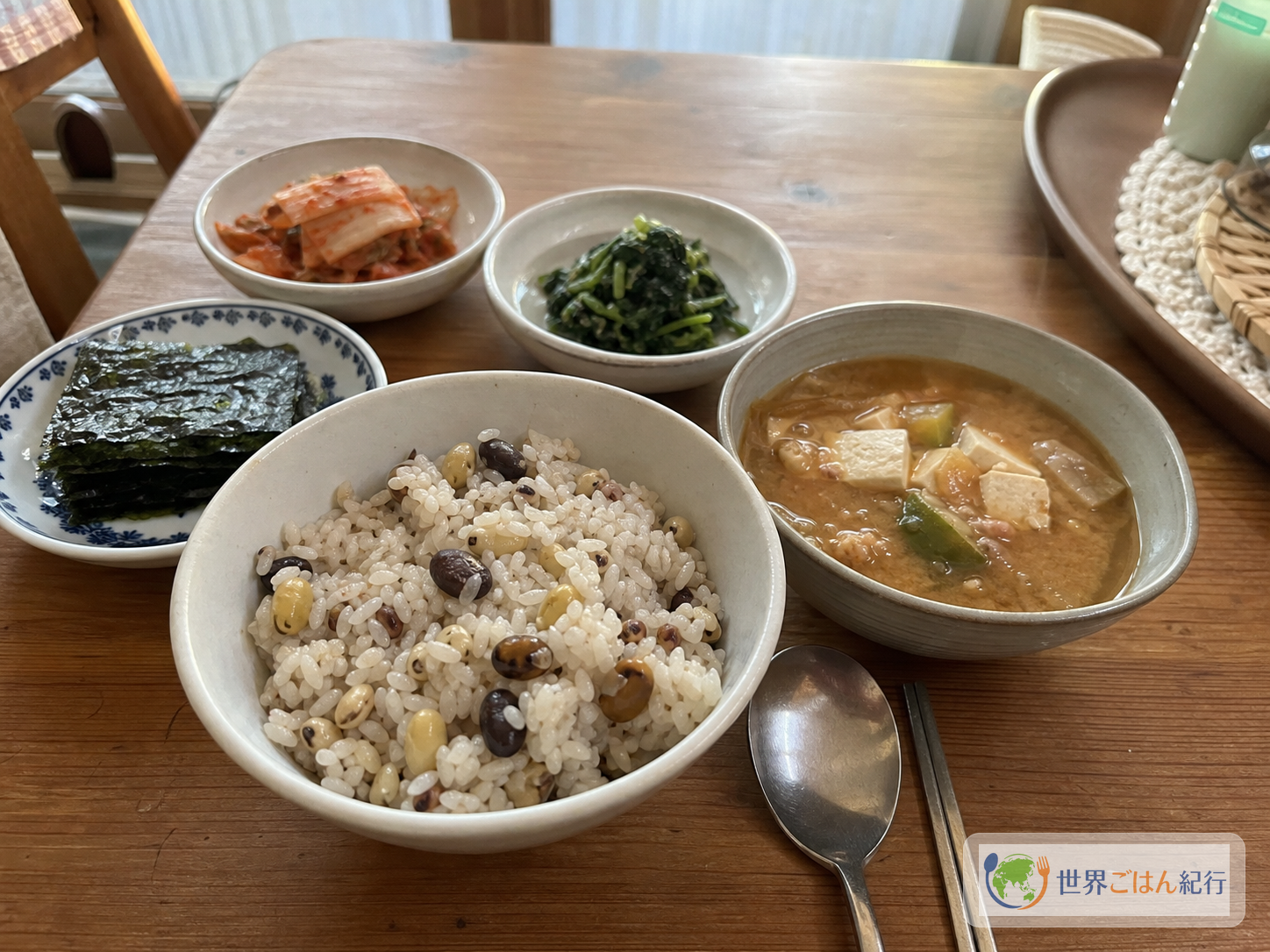 コンバプを茶碗に盛り、キムチ、韓国海苔、テンジャンチゲ、ナムルを並べた韓国の家庭の食卓