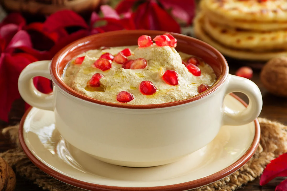 クリーム色のくるみソースに覆われたジョージアのサチヴィ。ザクロの実とコリアンダーが飾られた伝統の冷製鶏肉料理