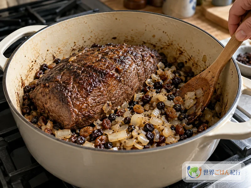 Cozinham-se as uvas-passas e a cebola picada ao redor da carne dourada na panela