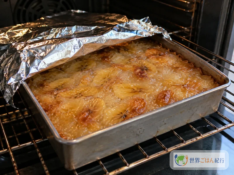 Banana dough baked to a translucent amber in a baking dish in the oven with the foil removed
