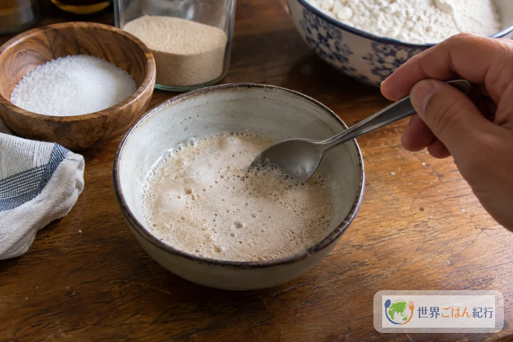Fine bubbles on the surface of dry yeast dissolved in lukewarm water in a small bowl