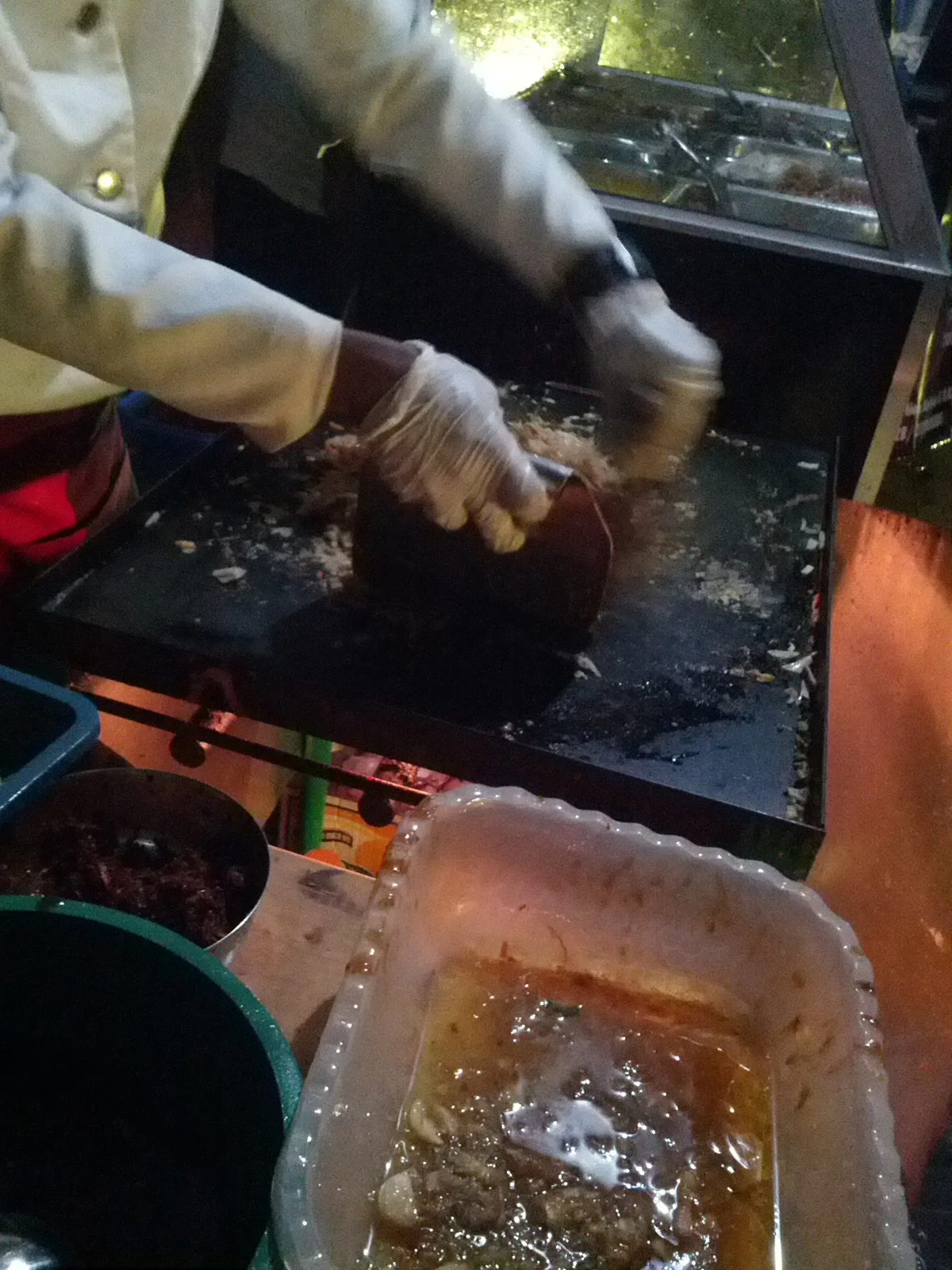 屋台の鉄板でコットゥが作られている様子。金属ヘラでロティが刻まれている