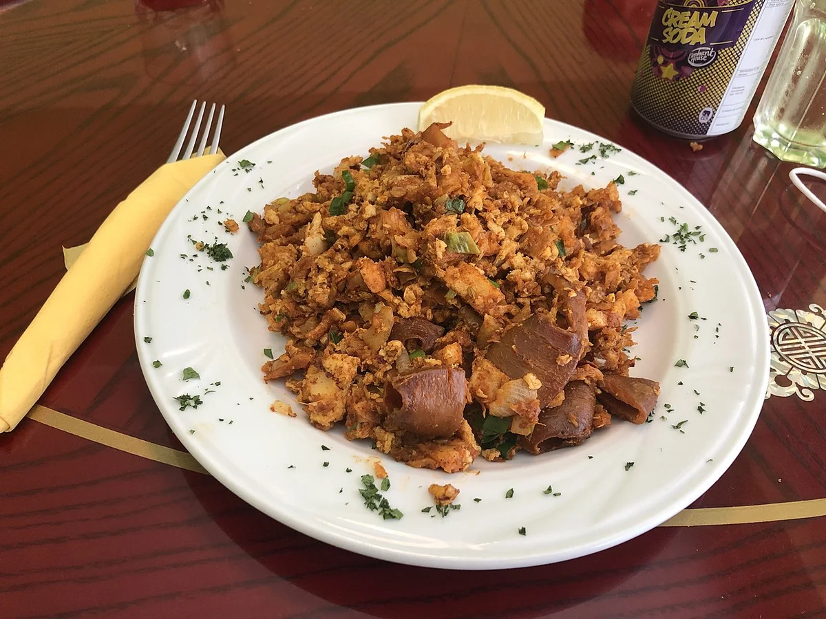 レストランで供されるシーフードコットゥ。パセリが散らされた白い皿にレモンが添えられている