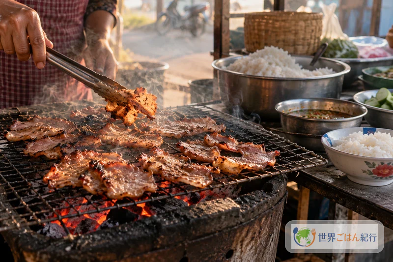 早朝のカンボジアの路上で、炭火の網に薄切り豚肉を並べて焼く屋台
