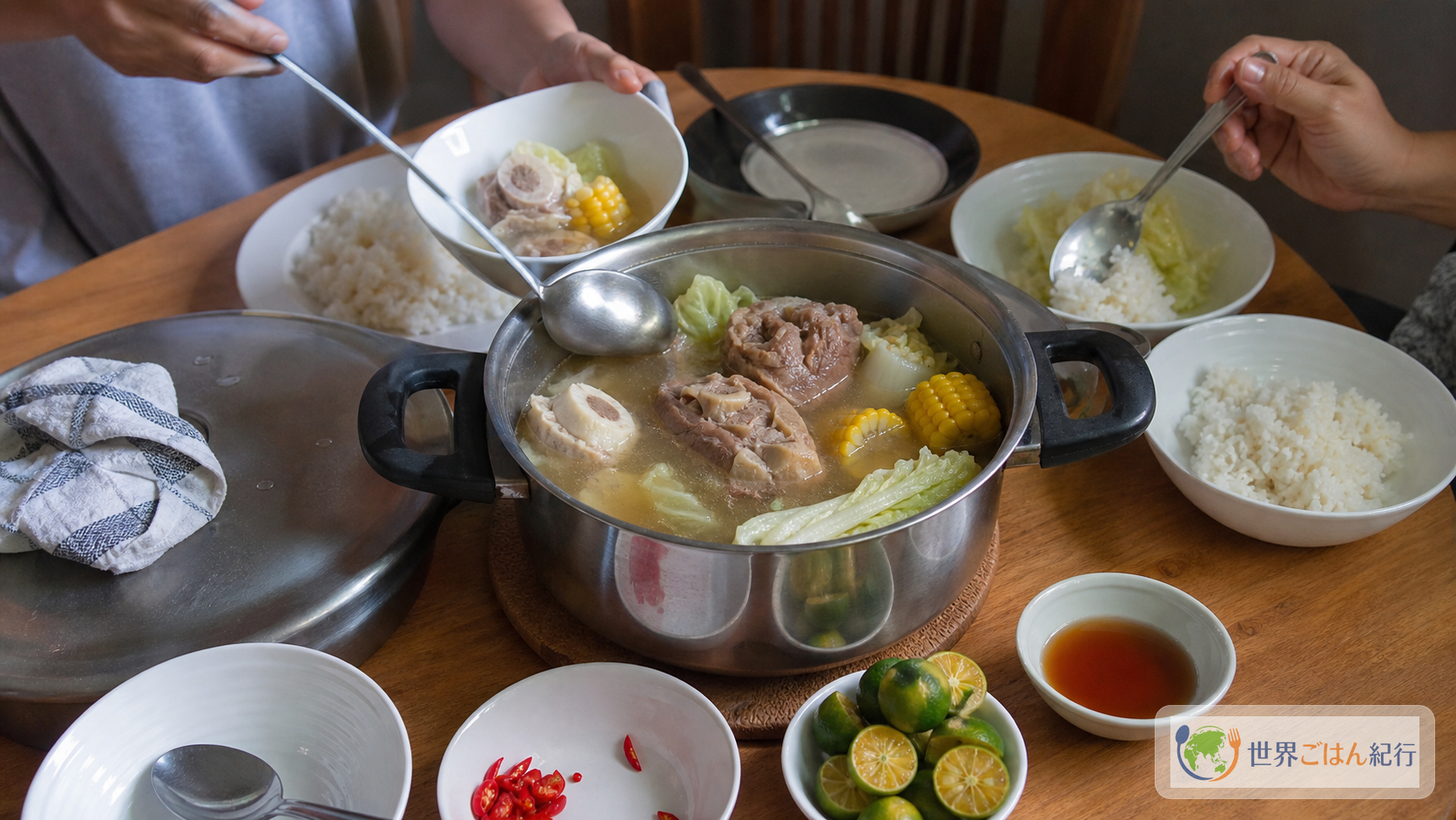 鍋のブラロを食卓で取り分け、ご飯、パティス、カラマンシーを添えたフィリピンの食卓