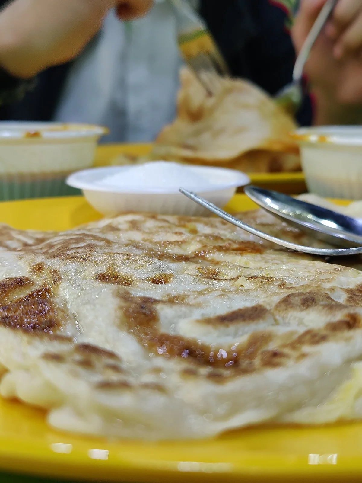 マレーシアのフードコートでロティ・チャナイを食べている風景
